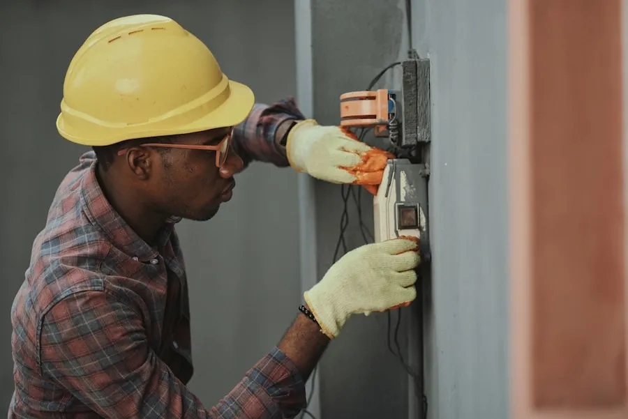 Pracownik budowlany w kasku podłączający instalację elektryczną